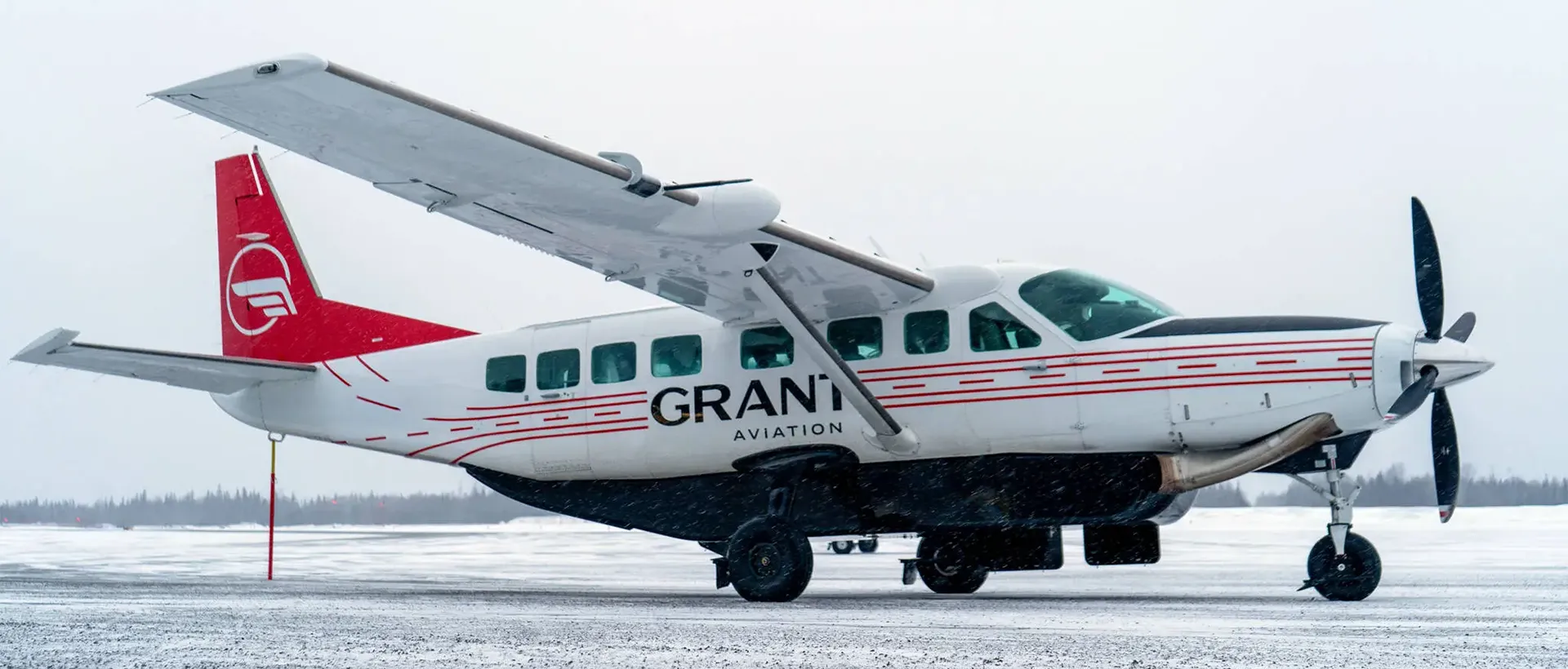 A Grant Aviation turboprop plane parked on a snowy winter runway in Alaska