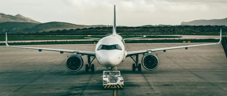 A large commercial passenger airplane being towed across an airport tarmac by a low-profile aircraft tug.