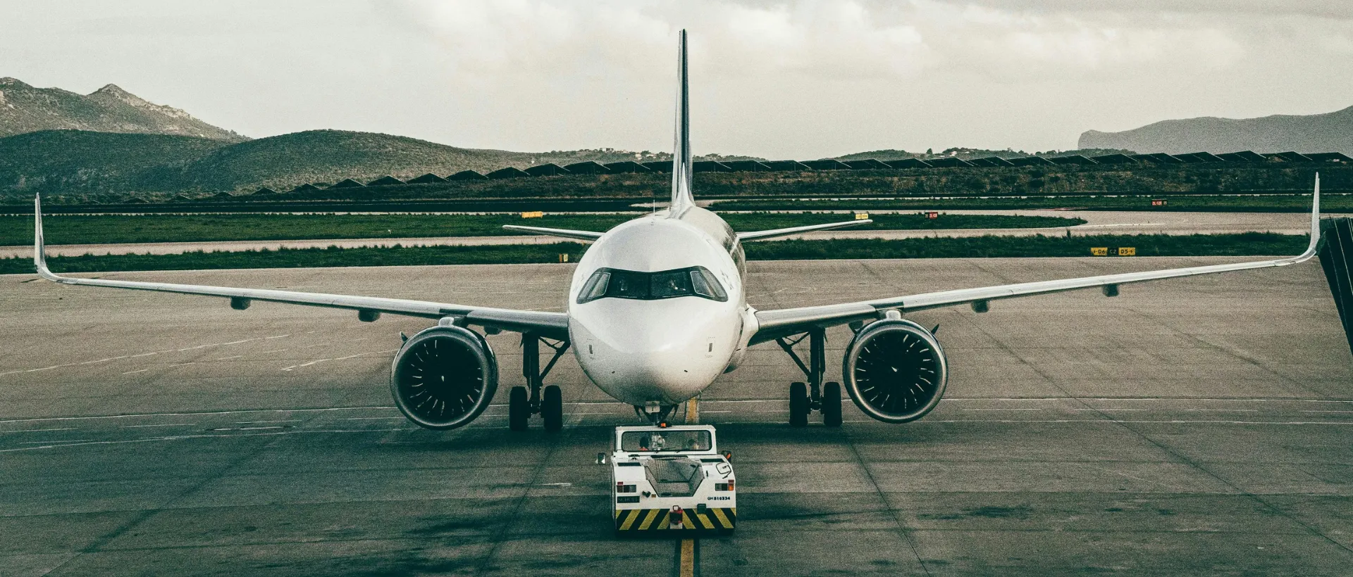 A large commercial passenger airplane being towed across an airport tarmac by a low-profile aircraft tug.